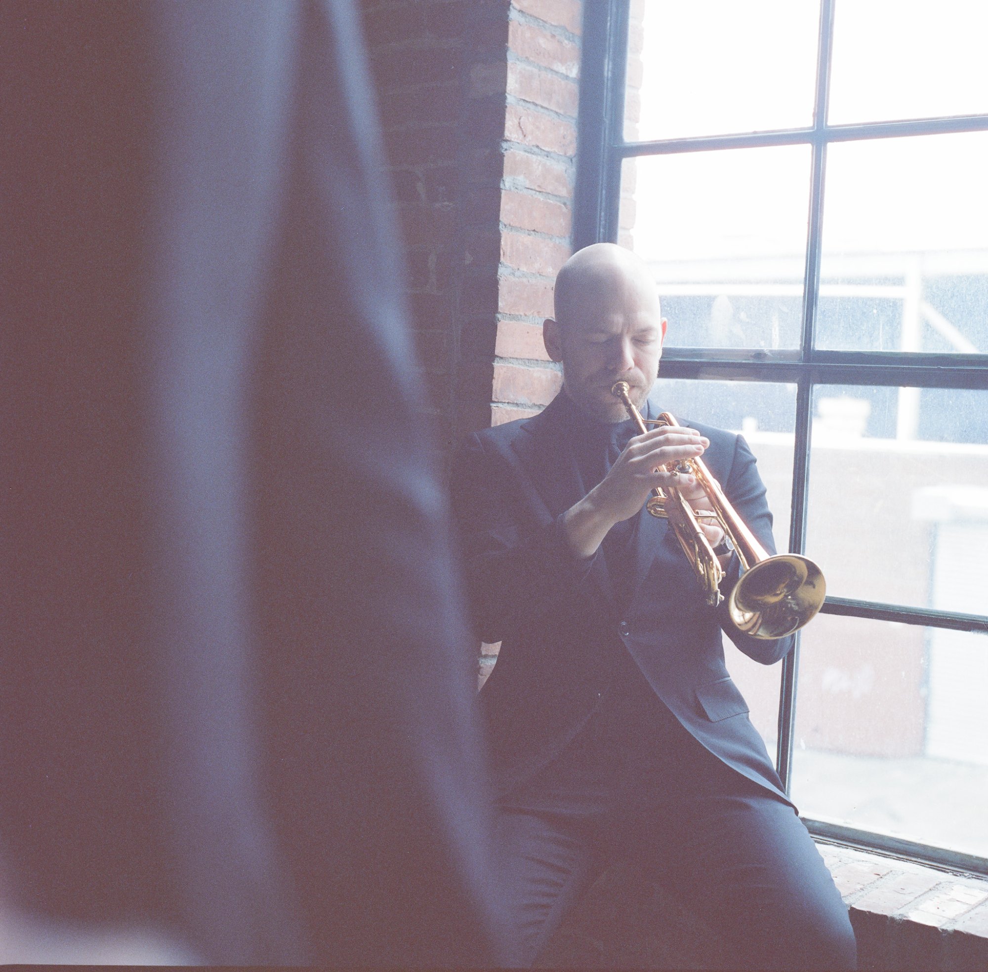 Caleb Hudson playing trumpet by window